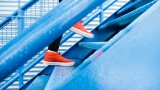 Mensch mit roten Sneakern läuft eine blaue Metalltreppe hinauf