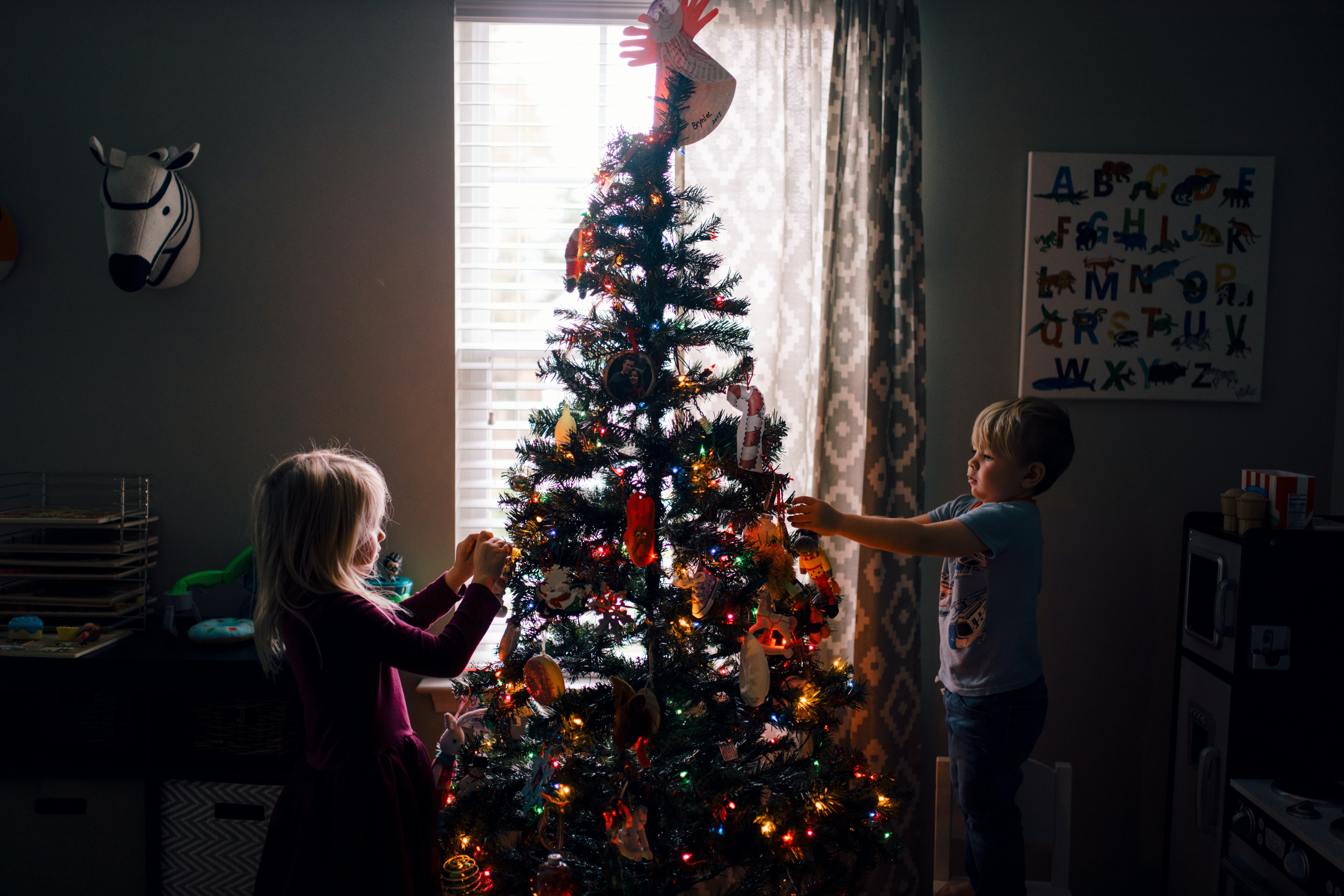 Kinder dekorieren einen festlich geschmückten Weihnachtsbaum