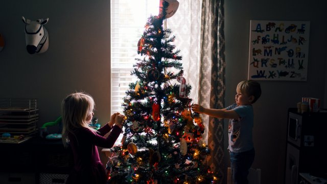 Kinder dekorieren einen festlich geschmückten Weihnachtsbaum