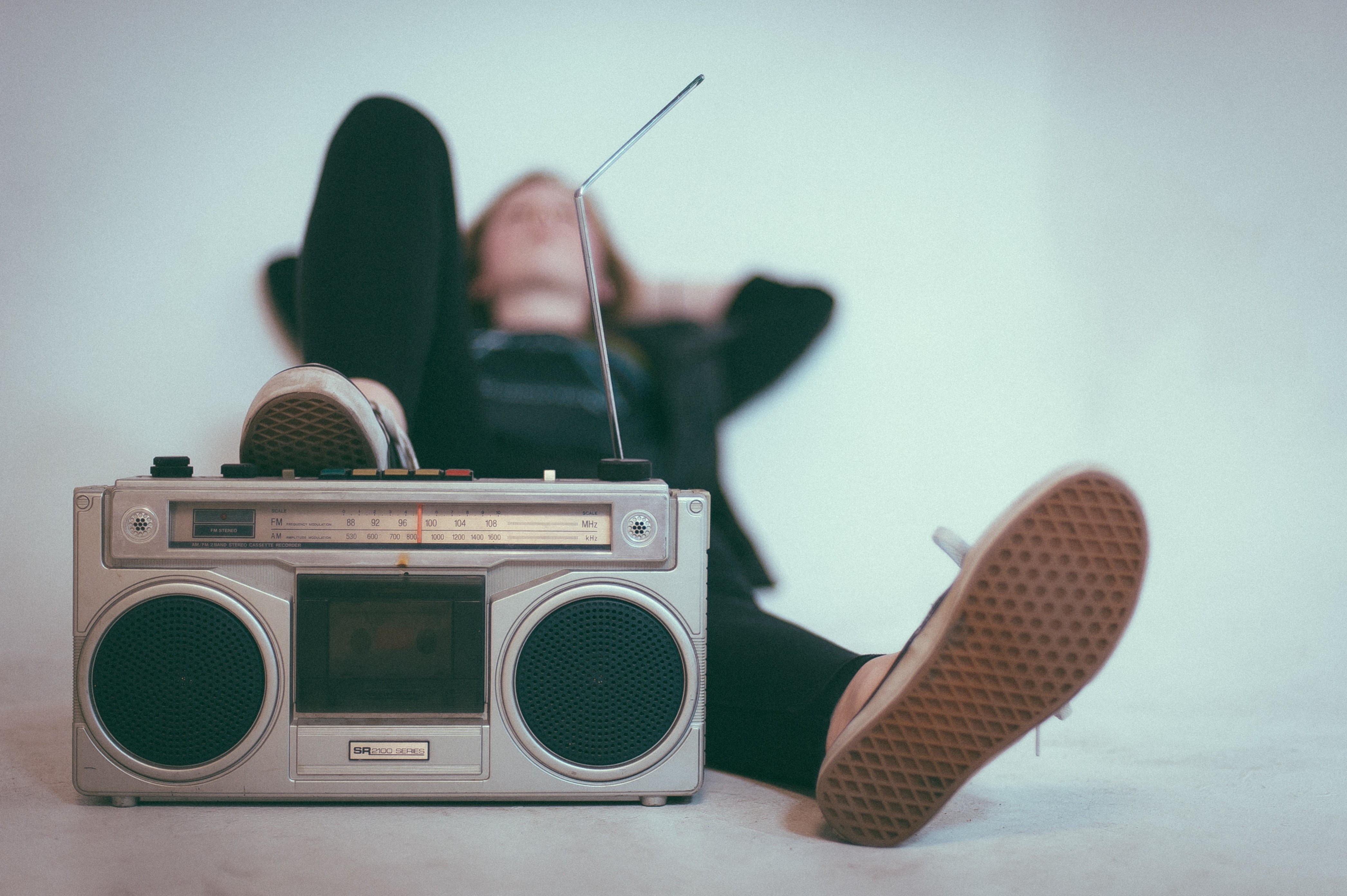 Ein Mensch hört im Liegen Musik aus einem alten Kassetten-Recorder