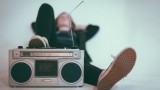 Ein Mensch hört im Liegen Musik aus einem alten Kassetten-Recorder