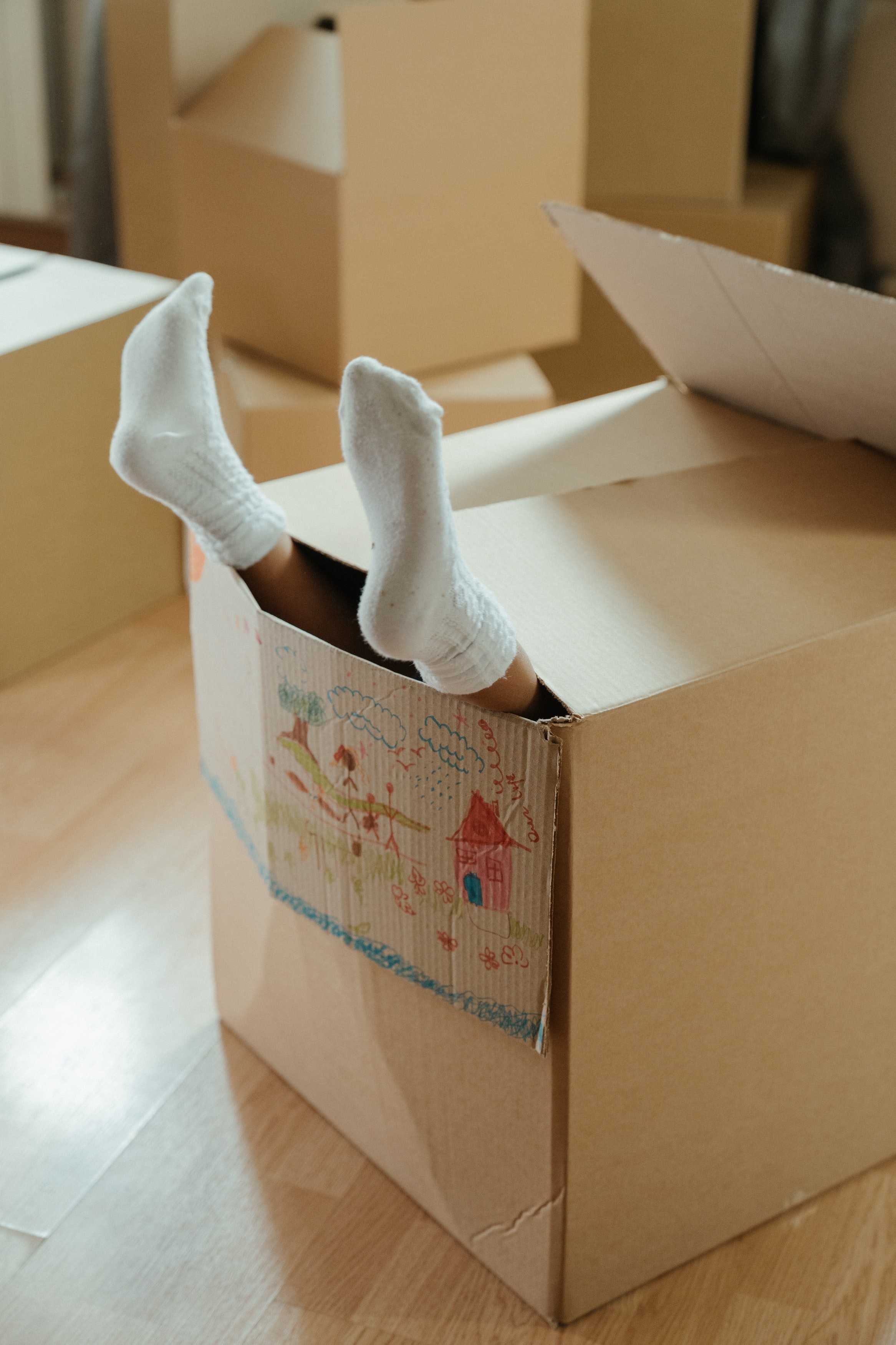 Füße mit weißen Socken schauen aus einem Umzugskarton heraus